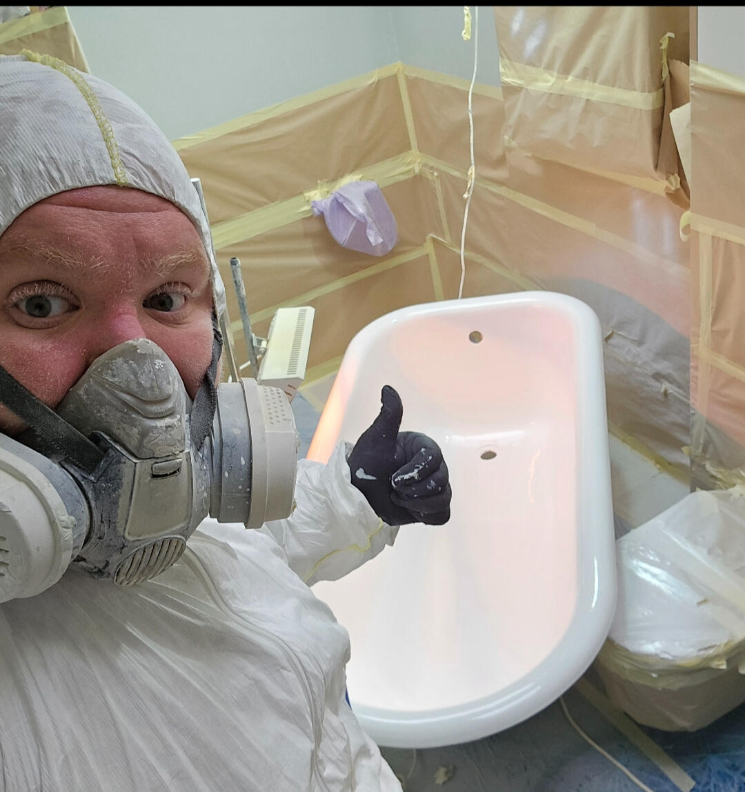 photo of glossy baths owner photo of glossy baths re-enamelling owner Seamus with a thumbs up, in ppe, in a room full of masking up and a completed bath in Coventry